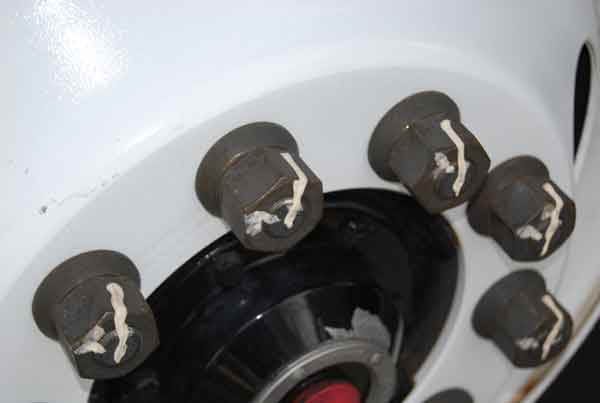 Image shows bus lug nuts with white markers that must line up to show nuts have not backed off from being tight.