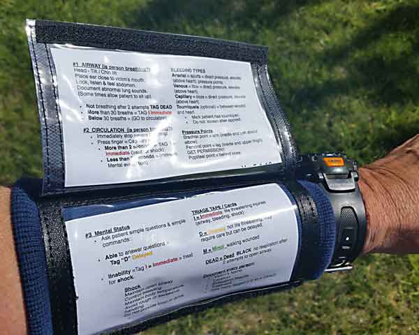 A wrist band is shown and the top page has been lifted up so the bottom of the first page shows the second triage procedures and then under this top page and resting next to the arm is the final of three pages showing the final triage procedures.