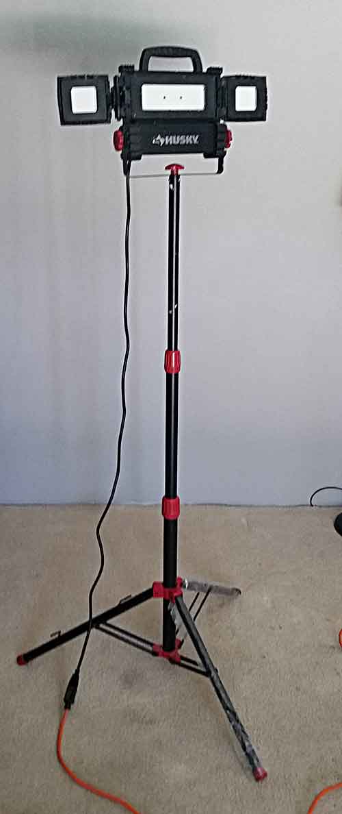 This image shows the work light extended to its full upward height. The image also shows the tripod at the bottom and the vertiacal three section stand which can be adjusted from two adjustment knobs.